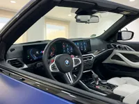 El lujoso habitáculo del BMW M4 Competition Cabrio 2023 en Ibiza, con un salpicadero moderno, volante y asientos de cuero blanco.