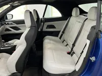 El lujoso interior del BMW M4 Competition Cabrio en Ibiza, mostrando sus asientos delanteros y traseros de cuero blanco, volante y salpicadero.