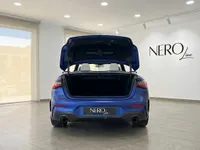 La vista trasera de un BMW M4 Competition Cabrio azul Frozen Portimao mate en Ibiza, con el maletero abierto, revelando el interior.