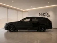 The black 2025 BMW M5 Touring is showcased in a modern showroom with the NEROline logo in Zurich.