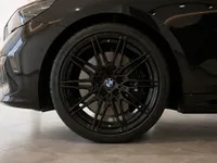 Close-up of the BMW M5 Touring's gloss black front wheel, showcasing its multi-spoke rim and brake caliper in Zurich.
