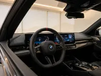The sophisticated interior of the 2025 BMW M5 Touring in Zurich, showcasing its modern steering wheel, digital displays, and carbon fiber trim.