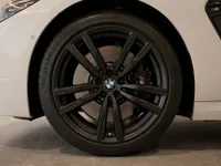 Close-up of the BMW M8 Competition Cabriolet's front wheel with black multi-spoke rim and white fender in Lausanne.