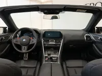 The black leather interior and dashboard of the BMW M8 Competition Cabriolet are visible from the driver's perspective in Lausanne.