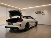 The white BMW M8 Competition Cabriolet is shown from the rear with its trunk open and convertible top down in Lausanne.