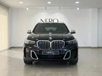 マドリードのショールームで、特徴的なグリルとヘッドライトを披露する黒い2025年型BMW X5 M Armoredの正面図。