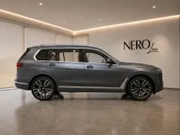 The metallic dark grey 2023 BMW X7 is shown in a showroom, highlighting its elegant side profile in Lausanne.