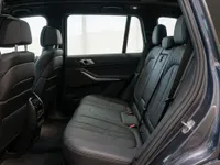 The luxurious rear interior of the 2023 BMW X7 in metallic dark grey, showcasing spacious black leather seats in Lausanne.