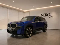 The deep blue BMW XM performance SUV is showcased in a modern showroom with the NEROline logo on the wall in Lausanne.