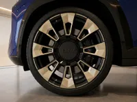 Close-up of the BMW XM's distinctive two-tone wheel and tire, showcasing the gloss Deep Blue bodywork in Lausanne.