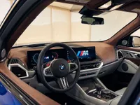 The luxurious interior of the 2023 BMW XM in Lausanne, featuring its sophisticated brown leather dashboard, digital screens, and steering wheel.