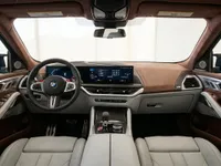 The luxurious interior of the 2023 BMW XM in Lausanne, featuring its advanced cockpit, digital dashboard, and brown leather trim.