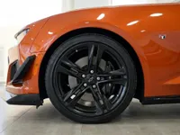 La rueda delantera y el guardabarros del Chevrolet Camaro Cabriolet 6.2 Naranja Metálico Brillante se muestran prominentemente en Alicante.
