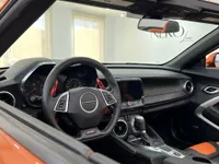 El interior del Chevrolet Camaro Cabriolet 6.2 en Alicante, mostrando el salpicadero negro, el volante y los asientos con detalles naranjas.