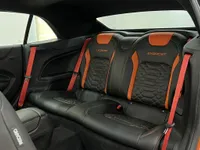 Los asientos traseros de cuero negro y naranja con cinturones rojos del Chevrolet Camaro Cabriolet 6.2 en Alicante.