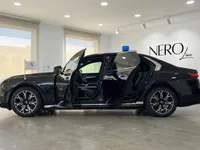 黒いBMW 7 Protection装甲車が、4つのドアがすべて開いており、屋根に青いライトを付けて、マドリードのショールームで横から撮影されています。