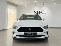 El Ford Mustang GT Convertible blanco se exhibe de frente, estacionado en el interior de un moderno showroom en Alicante.