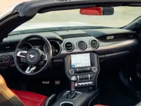 El interior del Ford Mustang GT Convertible en Alicante, mostrando el salpicadero, volante, infoentretenimiento y asientos de cuero rojo.
