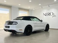 Ford Mustang GT Convertible blanco con capota blanda negra, aparcado en interior, visto desde el ángulo trasero tres cuartos en Alicante.