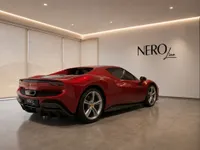 The glossy Rosso Imola metallic red Ferrari 296 GTB is parked in a modern showroom with the NEROline logo in Lausanne.