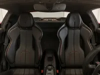 The luxurious black leather sport seats with red stitching and center console of the Ferrari 296 GTB interior in Lausanne.