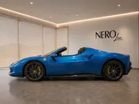 A blue Ferrari 296 GTS convertible with its top down, showcasing its sleek side profile in a modern showroom in Lausanne.