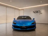 The front view of a gloss bright metallic blue Ferrari 296 GTS luxury car in a showroom in Lausanne.