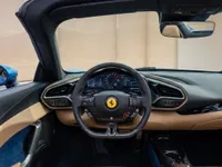 The luxurious cockpit of the Ferrari 296 GTS in Lausanne, featuring its advanced digital dashboard, sporty steering wheel, and elegant blue and tan interior.