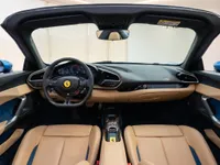The luxurious interior of the Ferrari 296 GTS in Lausanne, featuring a detailed view of the cockpit, dashboard, and tan leather seats with blue accents.