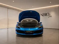 The bright metallic blue Ferrari 296 GTS is showcased from the front with its hood open, revealing the frunk in a showroom in Lausanne.