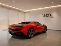 Red Ferrari 296 GTS from a rear three-quarter view, parked in a modern showroom in Zurich.