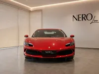 The red Ferrari 296 GTS is prominently displayed in a showroom, showcasing its sleek front design in Zurich.