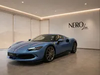 A striking blue Ferrari 296 GTS, captured from a front three-quarter angle, showcased in a modern NEROline showroom in Zurich.
