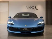 The blue Ferrari 296 GTS is showcased from a direct front view in a modern showroom in Zurich.