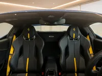 The luxurious interior of the Ferrari 296 GTS in Zurich, featuring black leather sports seats with striking yellow accents and matching seatbelts.