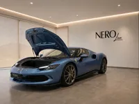 A blue Ferrari 296 GTS with its front hood open, showcasing its design in a modern Zurich showroom.