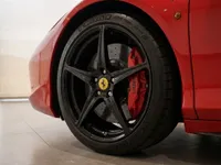 Close-up of the Ferrari 458 Spider's black alloy wheel and red brake caliper, showcasing its performance details in Zurich.