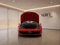 The red Ferrari 458 Spider is shown from the front with its hood open in a modern NEROline showroom in Zurich.