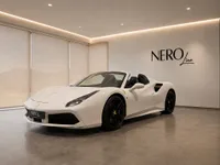 A gloss white Ferrari 488 Spider is showcased in a luxury showroom in Zurich, displaying its elegant front and side profile.