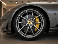 The front wheel and yellow brake caliper of a dark grey Ferrari 812 GTS in a showroom in Lausanne.