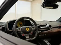 The luxurious interior of the Ferrari 812 GTS in Lausanne, featuring the steering wheel, yellow tachometer, and brown leather dashboard.