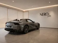 The grey Ferrari 812 GTS convertible is parked in a showroom with the NeroLine logo on the wall in Lausanne.
