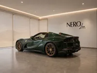 Ferrari 812 GTS in gloss dark green, parked indoors, shown from a rear three-quarter angle in Zurich.