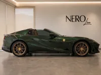 The gloss dark green Ferrari 812 GTS is showcased from its side profile in a modern showroom in Zurich.