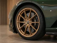 The Ferrari 812 GTS in gloss dark green showcases its bronze multi-spoke front wheel with black brake calipers and carbon ceramic disc in Zurich.