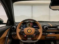 The luxurious cockpit of the Ferrari 812 GTS in Zurich, featuring its distinctive brown leather and carbon fiber steering wheel and dashboard.