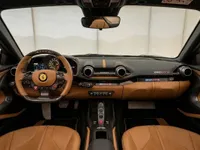 The luxurious interior of the Ferrari 812 GTS in Zurich, featuring a tan leather dashboard, steering wheel, and seats, visible from the driver's perspective.
