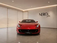 The stunning red Ferrari 812 Superfast is showcased from the front in a modern showroom with the NEROline logo in Lausanne.