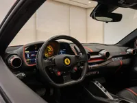 The luxurious cockpit of the Ferrari 812 Superfast in Lausanne, featuring its distinctive steering wheel, digital dashboard, and red interior accents.