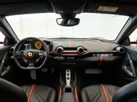 The luxurious interior of the 2020 Ferrari 812 Superfast in Lausanne, showcasing its dashboard, steering wheel, and black seats with red accents.